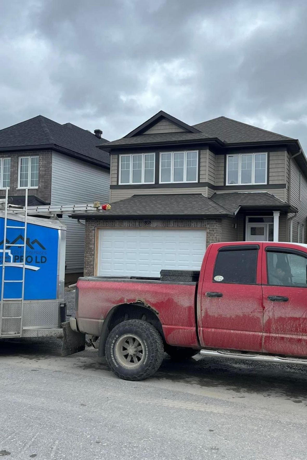 Maison en construction avec camion et remorque stationnés devant façade au Québec